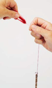 person drawing out fibers from unspun yarn to loop in to leader yarn